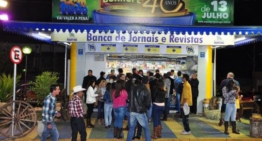 Fachada da Banca Martins à noite, com clientes em frente
